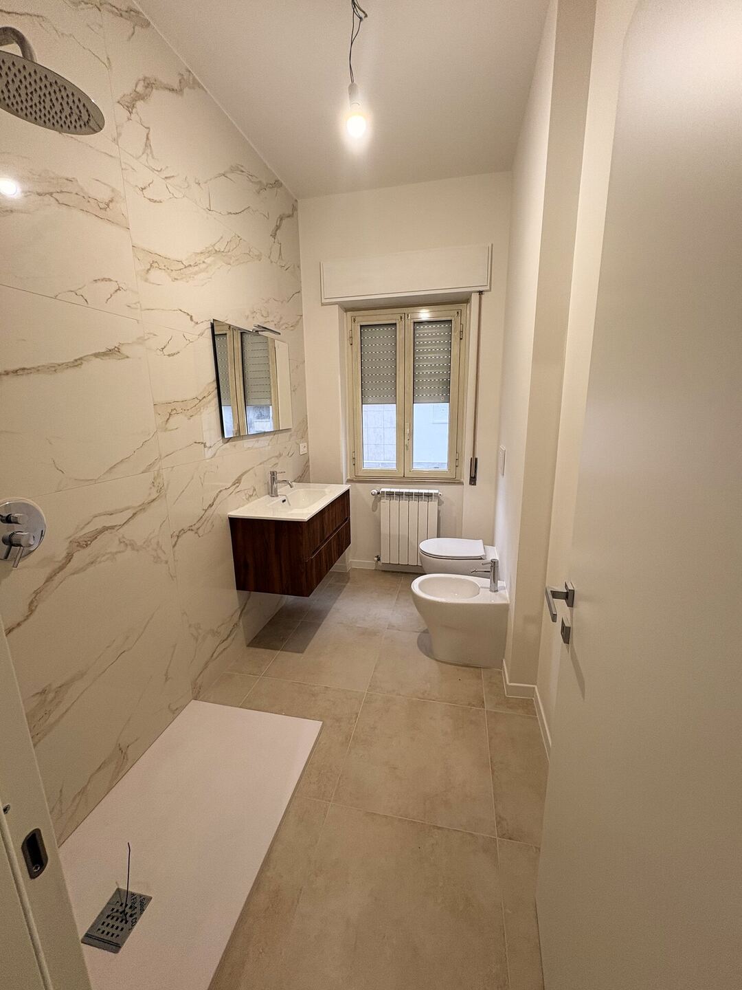 Il bagno dopo i lavori: rivestimenti effetto marmo, doccia a filo pavimento