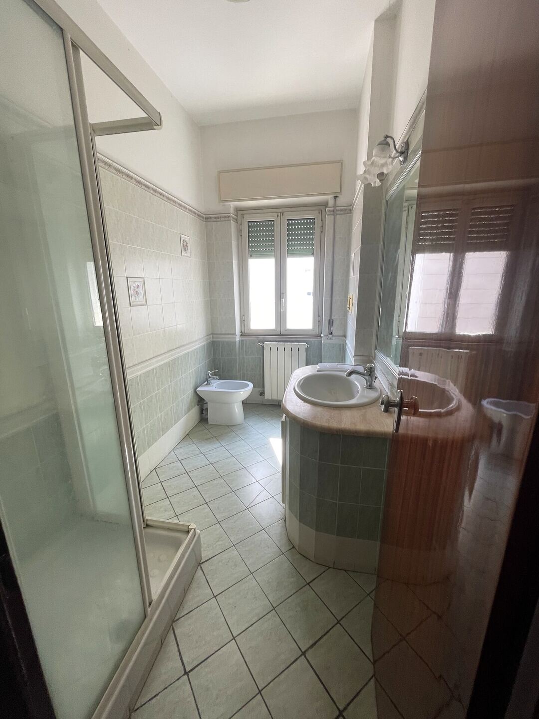 Il bagno prima dei lavori: piastrelle datate, vecchio box doccia